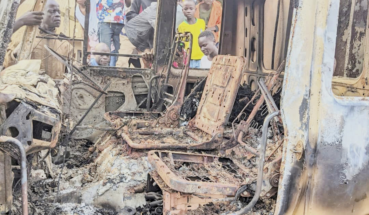 People gather around the charred remains of a burned vehicle following a deadly attack in Komanda, Ituri province of eastern Congo, Sunday, July 27, 2025. (AP)