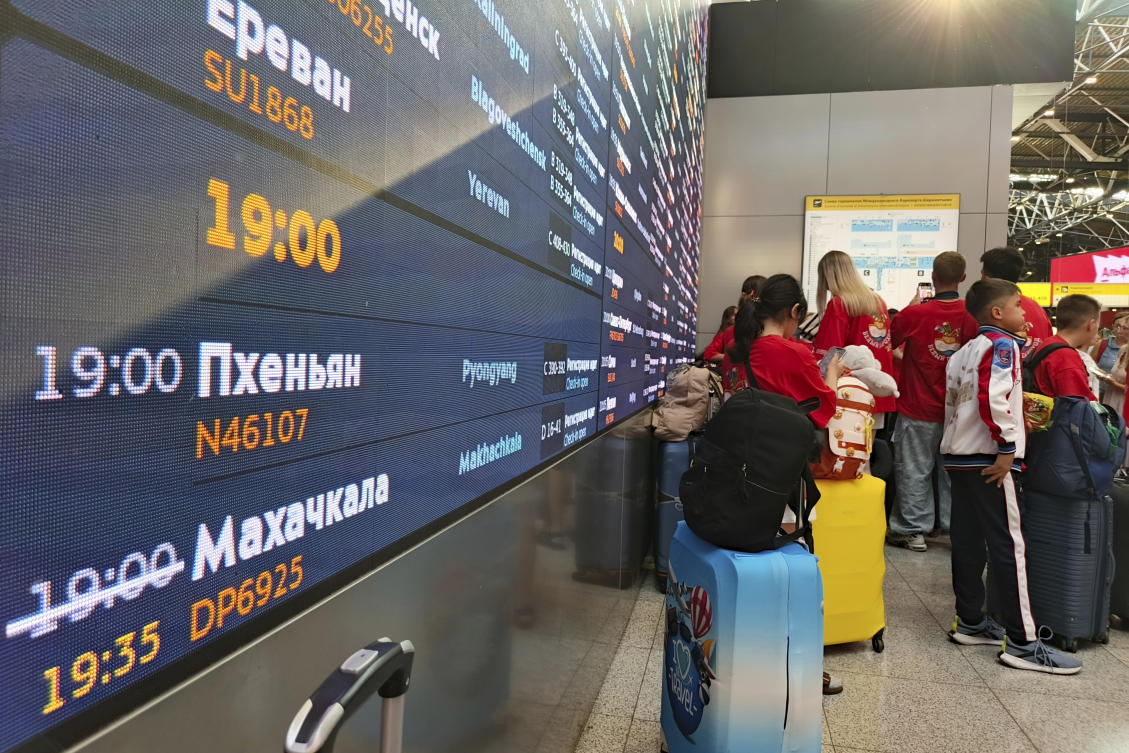 Passengers lineup to check-in for the first flight connecting Moscow and Pyongyang with a flight information board showing take-off time at Moscow's Sheremetyevo International airport on July 27, 2025. (AP Photo)