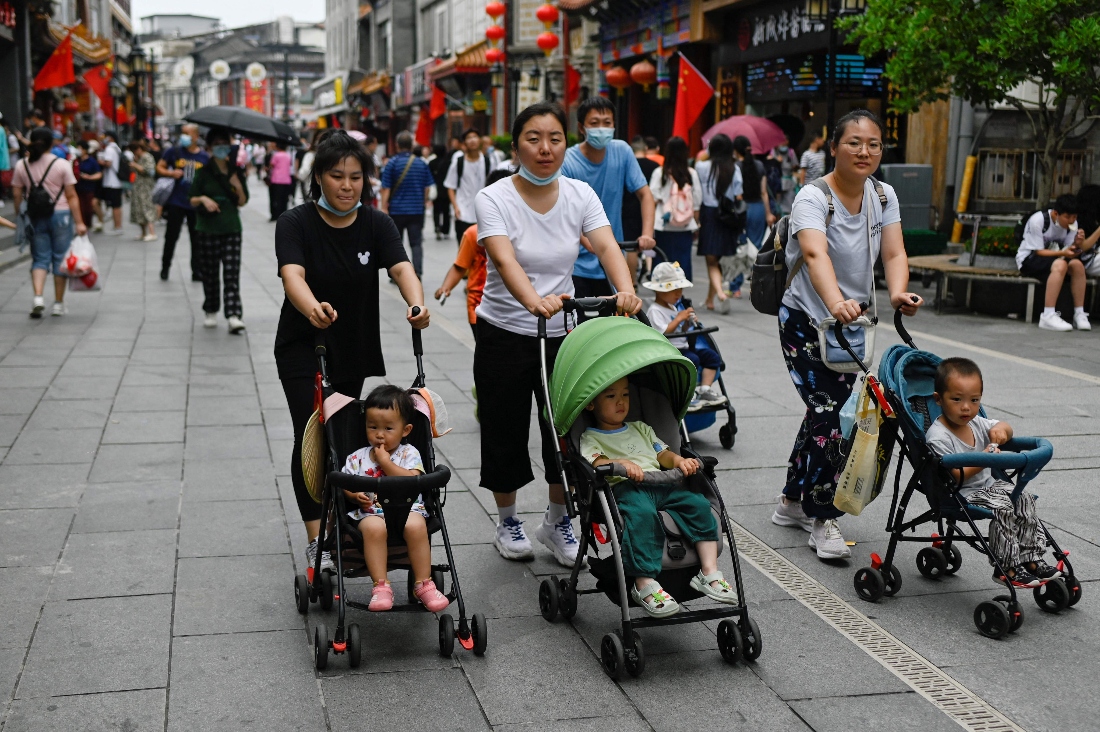 Women push baby strollers along a business street in Beijing, China. (AFP)