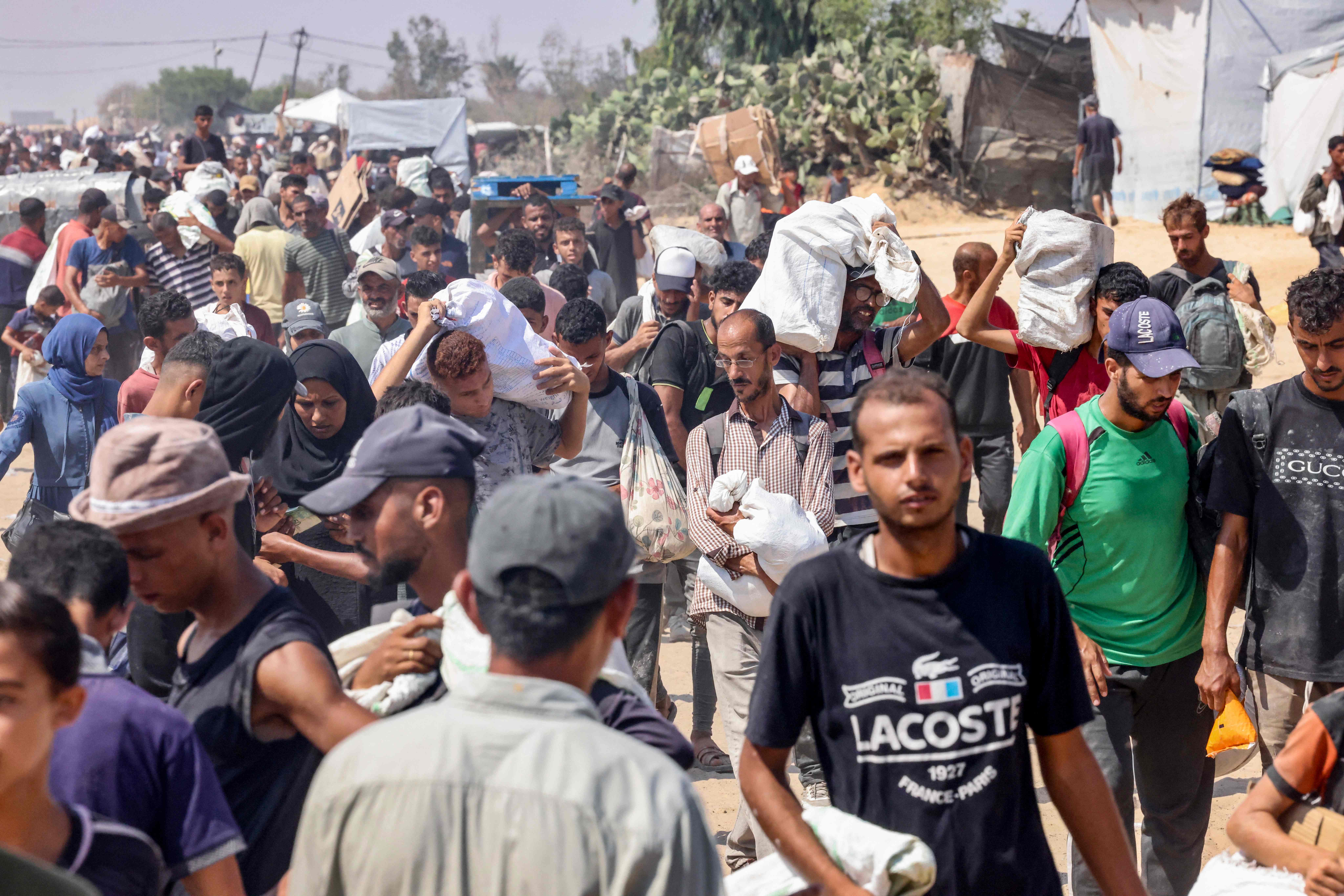 Palestinians carry personal belongings as they walk in the Mawasi area of Rafah in the southern Gaza Strip on July 28, 2025. (AFP)