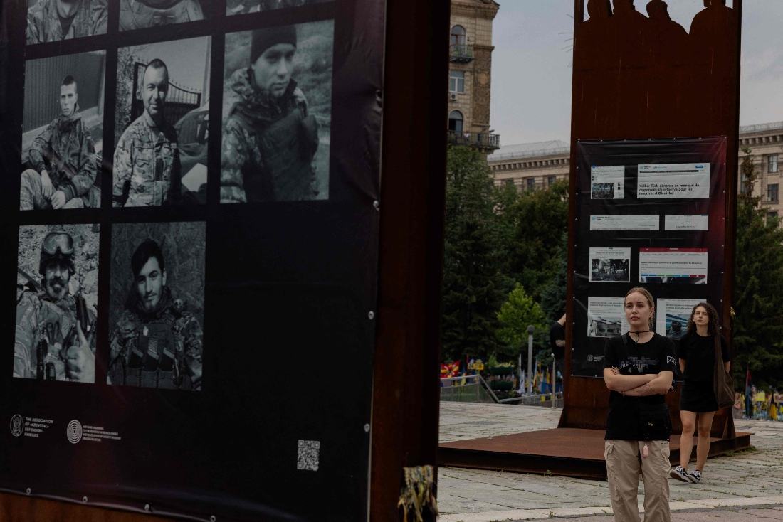 Ukrainian women look at at an exhibition during a memorial event to mark the third anniversary of the Olenivka prison attack, at Independence Square in Kyiv, Ukraine. (AFP)