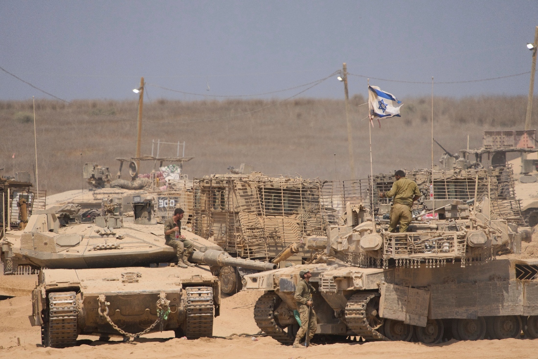 Israeli soldiers sitting on their tanks in a staging area on the border with Gaza Strip, in southern Israel. (AP)