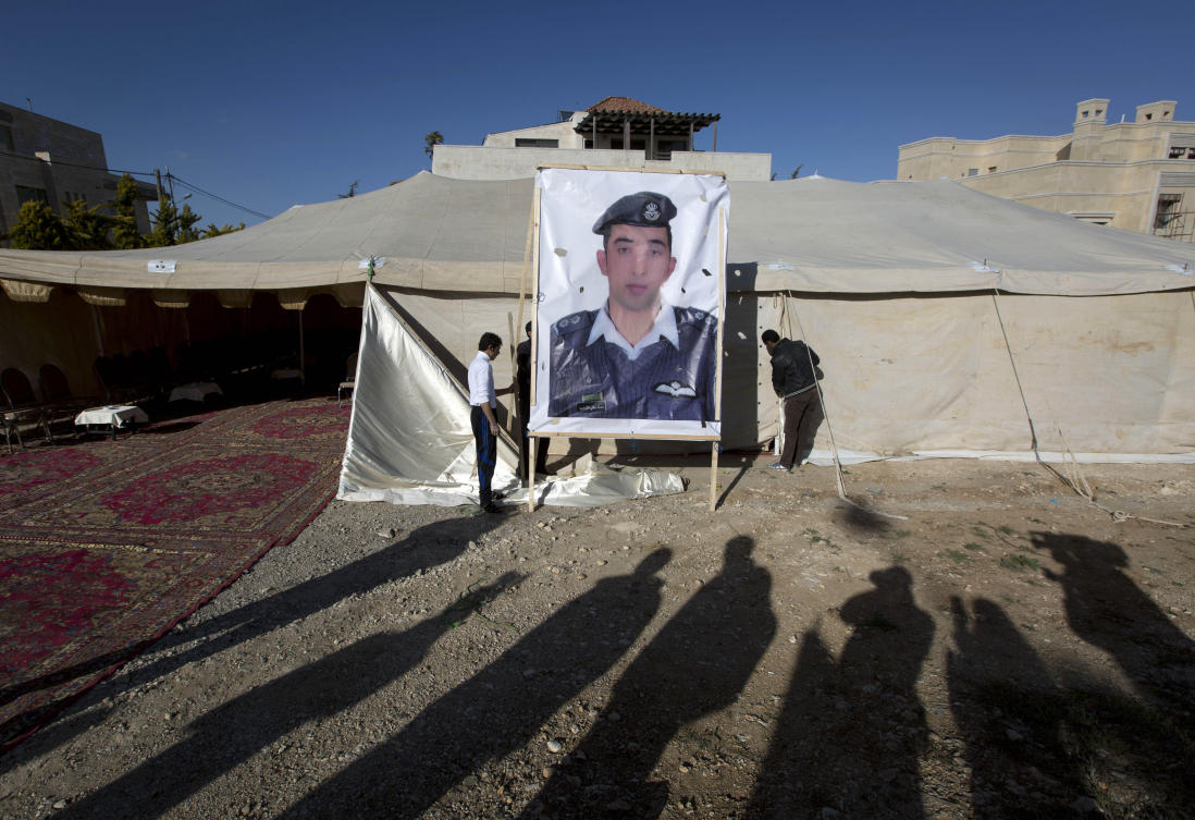 Workers raise a banner with a photo of Jordanian pilot Lt. Mu'ath al-Kaseasbeh, held captive by the Daesh group, outside a tent for supporters in Amman, Jordan, on Jan. 30, 2015. (AP Photo/Nasser Nasser, File)