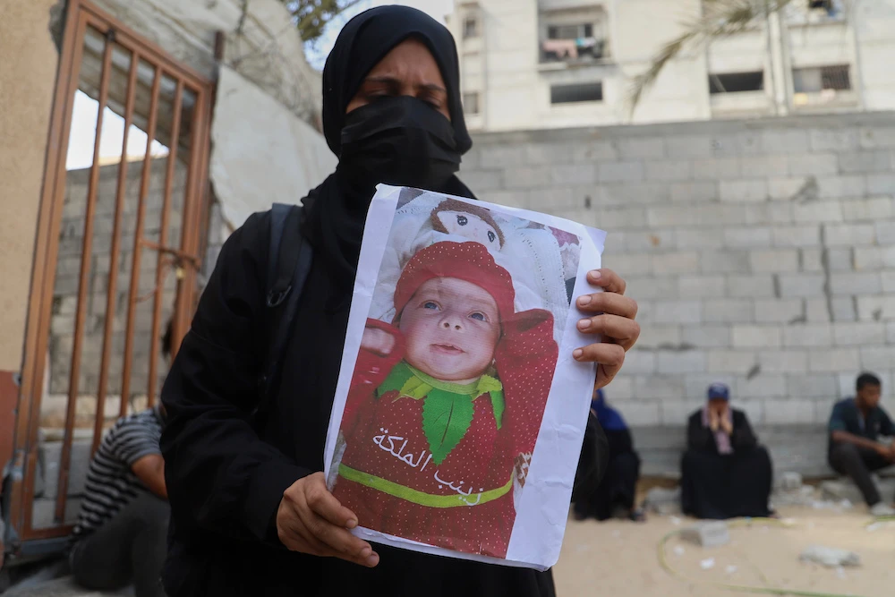 Esraa Abu Halib shows to journalists a photo of her 5-month-old baby, Zainab, who died from malnutrition-related causes. (AP)