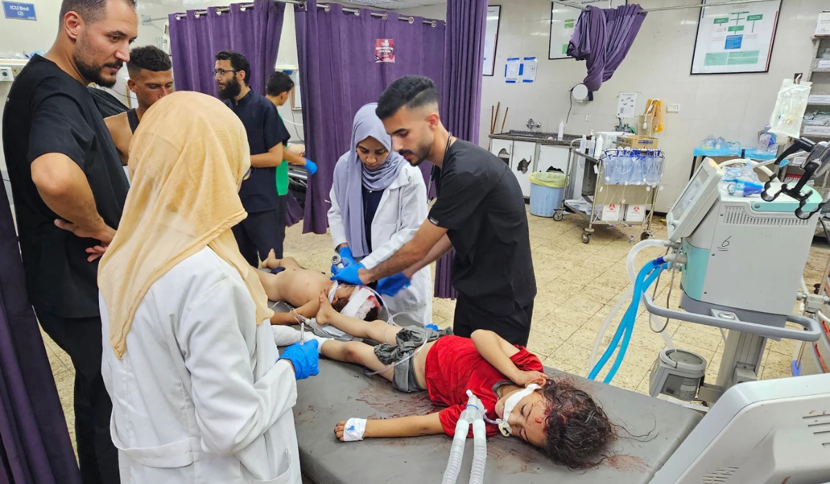 Palestinian medics attend to children wounded in an Israeli strike on a camp for displaced people in Gaza. (AFP)
