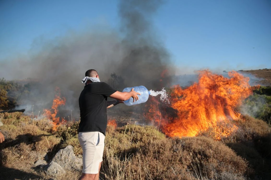 A man attempts to extinguish a wildfire in the Cesme district of Izmir, Turkiye, on July 3, 2025. (AFP)