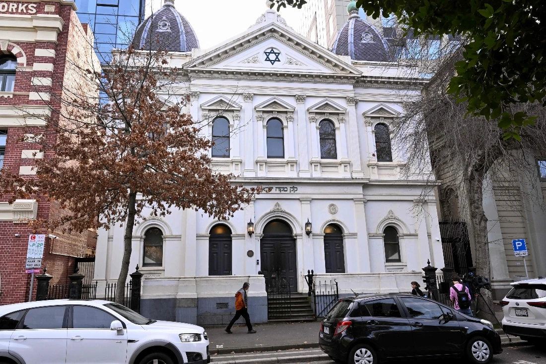 People pass the burnt front entrance of the East Melbourne Synagogue in Melbourne, Australia. (AFP)