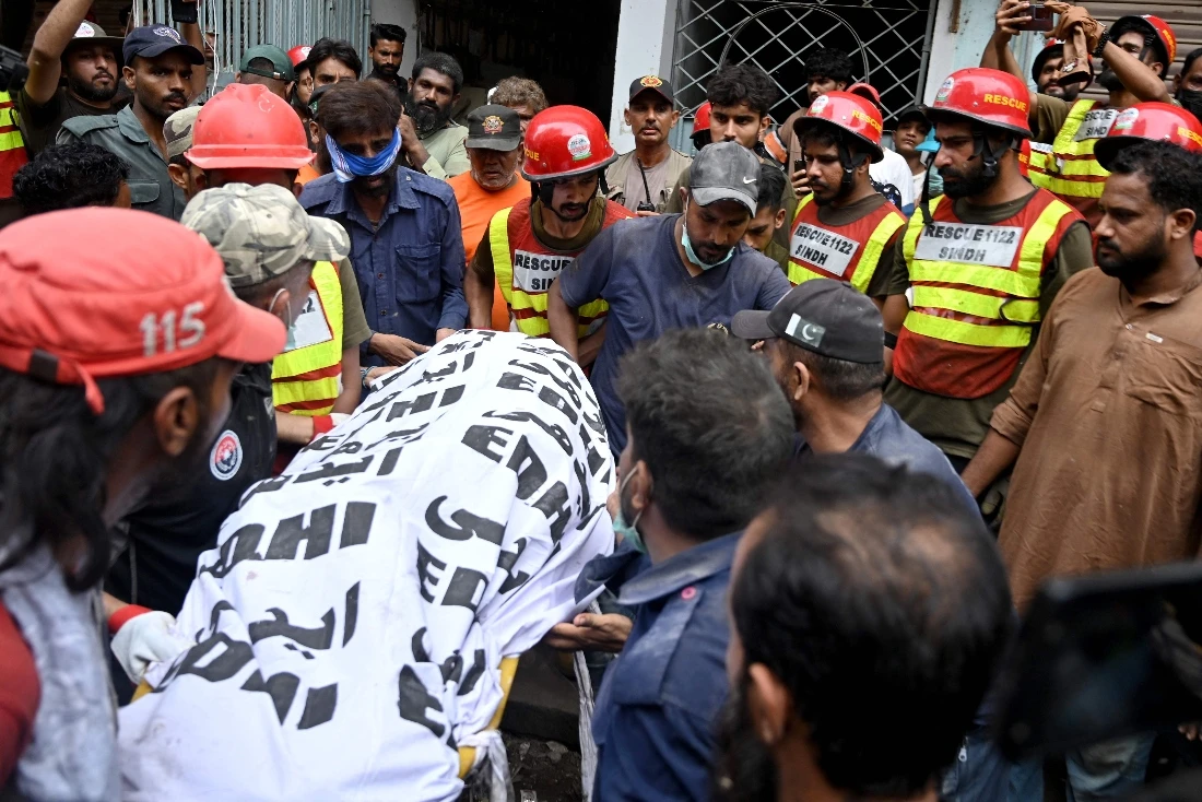 Rescue workers recover a victim's body during a search operation amid the debris of a collapsed residential building in Karachi, Pakistan. (AFP)