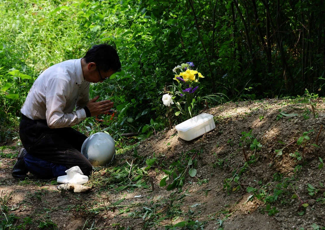 Rebun Kayo offers a prayer to the bone fragments he has found and placed in a plastic box at a site on Ninoshima Island, Japan. (Reuters)