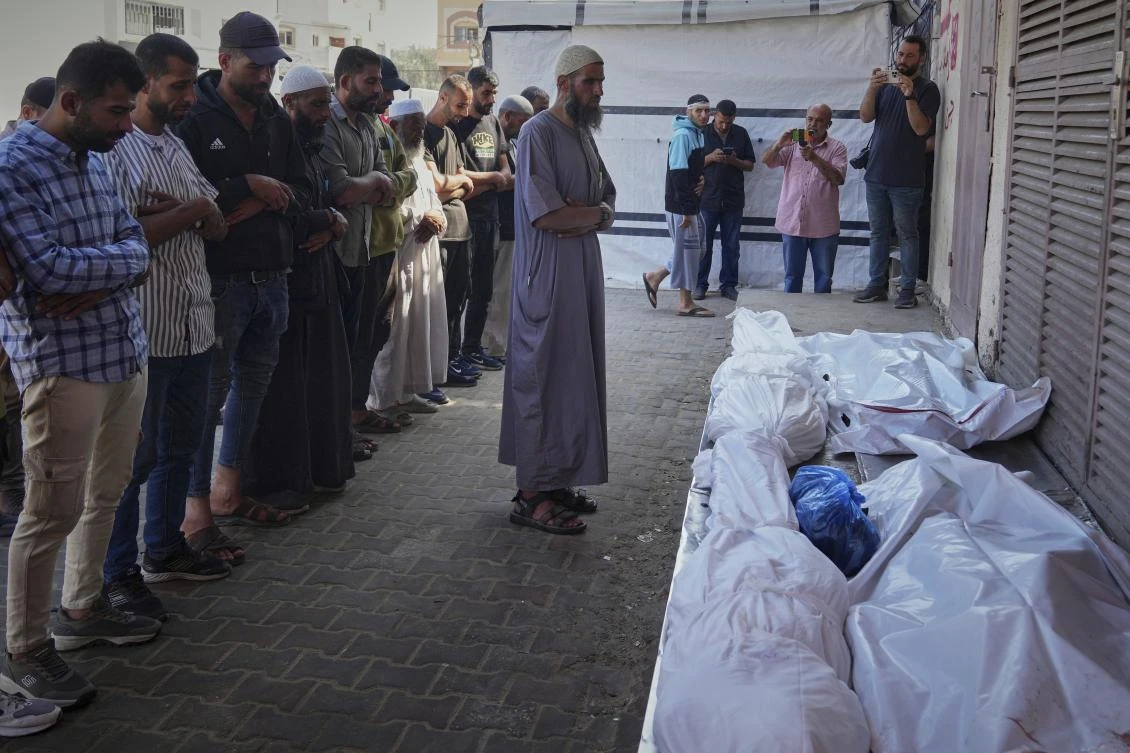 Palestinians pray over the bodies of 10 people, including two women and five children, killed in an Israeli strike while they were waiting to receive nutritional supplements at a Project Hope-run medical clinic in Deir Al-Balah, Gaza Strip, on Thursday. (AP)