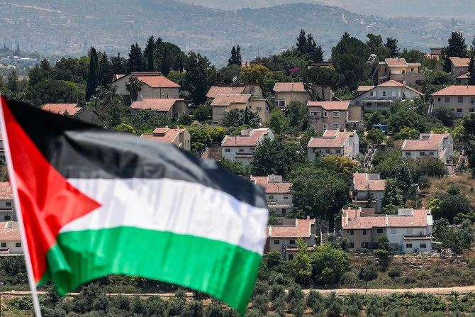 A Palestinian flag flies opposite Israeli settlements in the occupied West Bank. A postponed Saudi-Franco conference to discuss Palestinian statehood has been rescheduled for July 28 to 29. (AFP/File Photo)