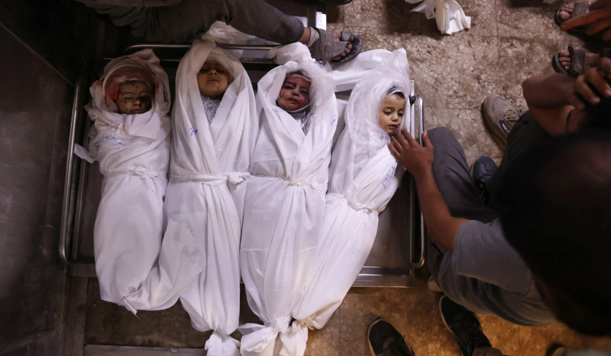 Palestinian men mourn over the shrouded bodies of children, killed in overnight Israeli strikes, in the morgue of the Al-Shifa hospital in Gaza City on July 15, 2025. (AFP)