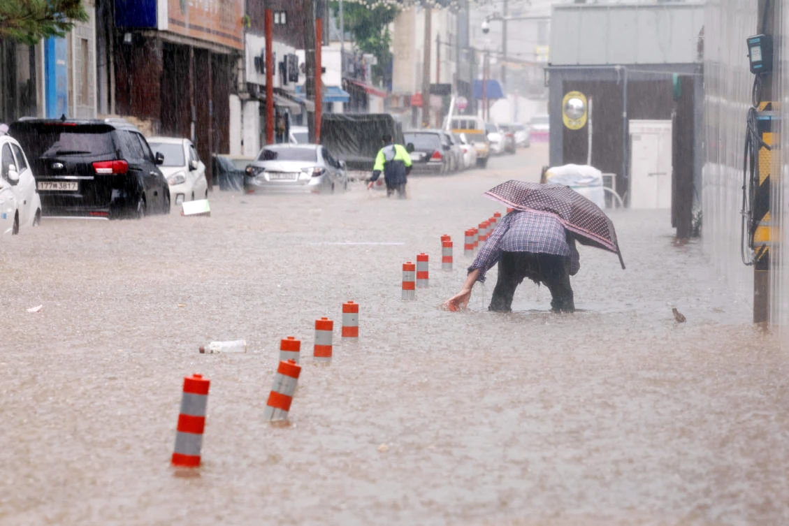 A man makes his way through a flooded street, caused by torrential rain, in Gwangju, South Korea. (REUTERS)