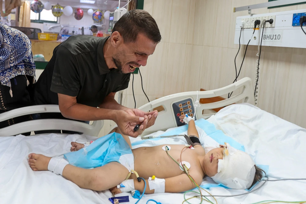 Palestinian father Hatem Al-Nouri, who lost two of his children, Omar and Amir, in the July 10 Israeli strike while they were queuing for supplements near a medical center, reacts as he accompanies his son Siraj, who was wounded in the same strike, at Al-Aqsa Martyrs Hospital in Deir al-Balah, in the central Gaza Strip, July 14, 2025. (Reuters)