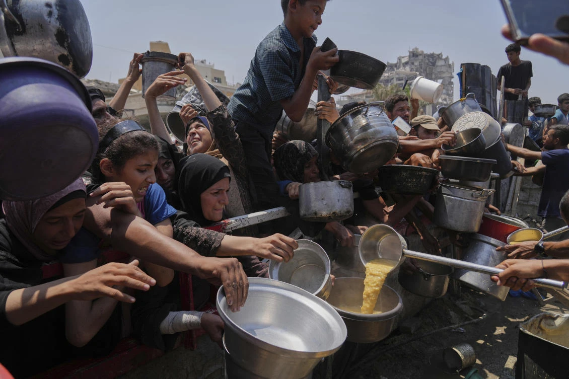 Palestinians struggle to get donated food at a community kitchen, in Gaza City, northern Gaza Strip, Saturday, July 26, 2025. (AP Photo/Abdel Kareem Hana)