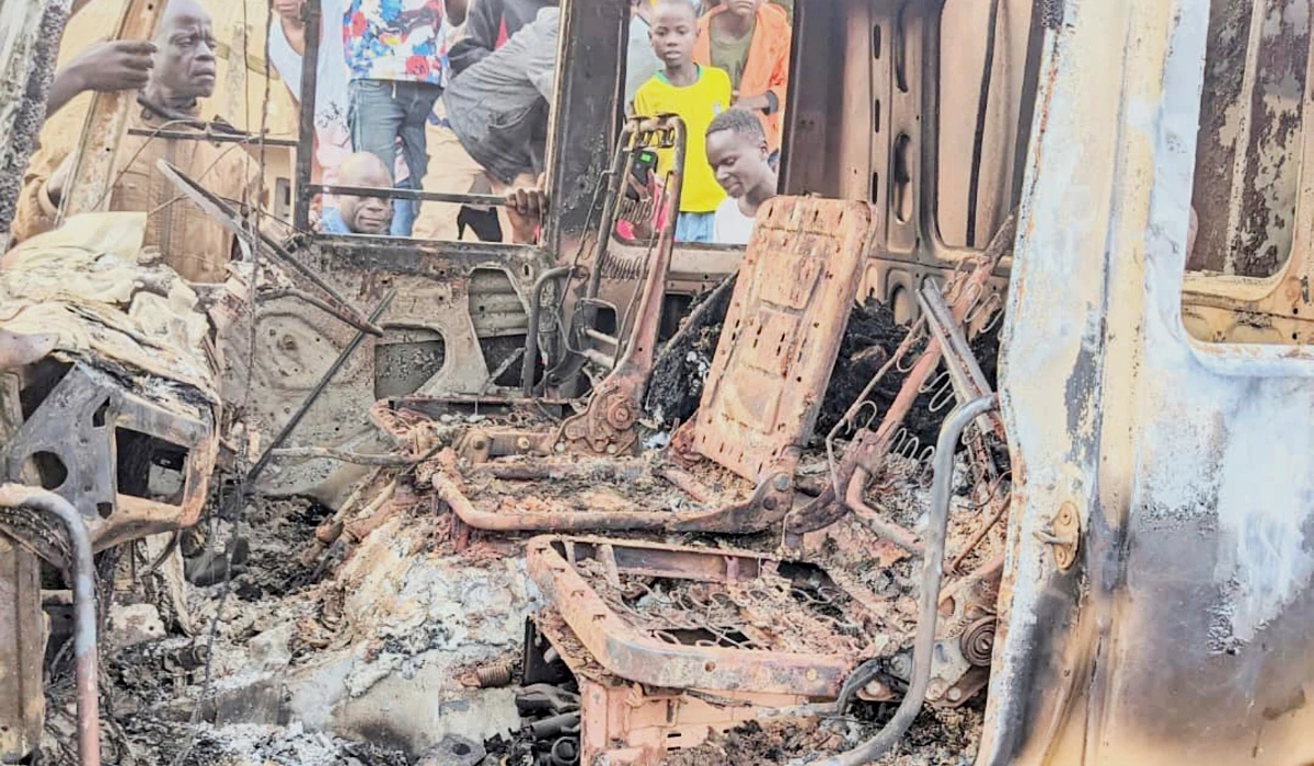 People gather around the charred remains of a burned vehicle following a deadly attack in Komanda, Ituri province of eastern Congo, Sunday, July 27, 2025. (AP)