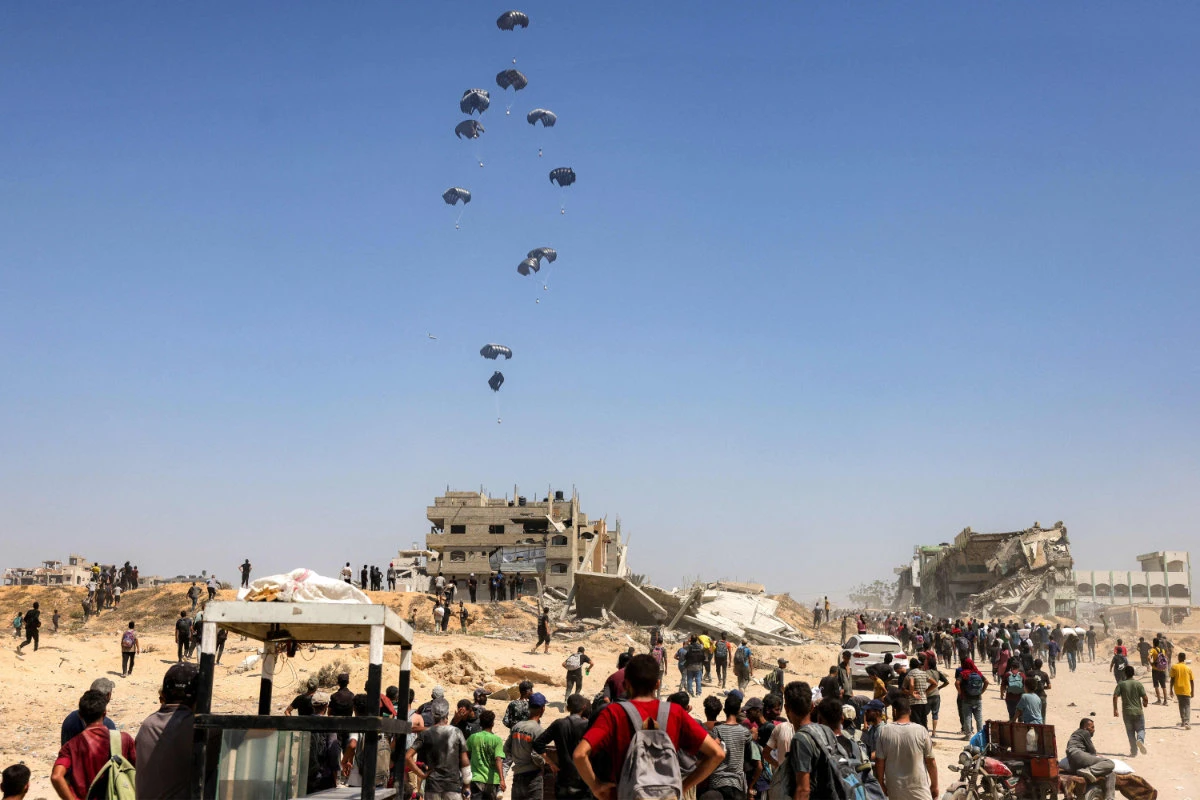 People gather as Jordanian and Emirati plane military transport aircraft drop humanitarian aid on the northern Gaza Strip on July 27, 2025. (AFP)