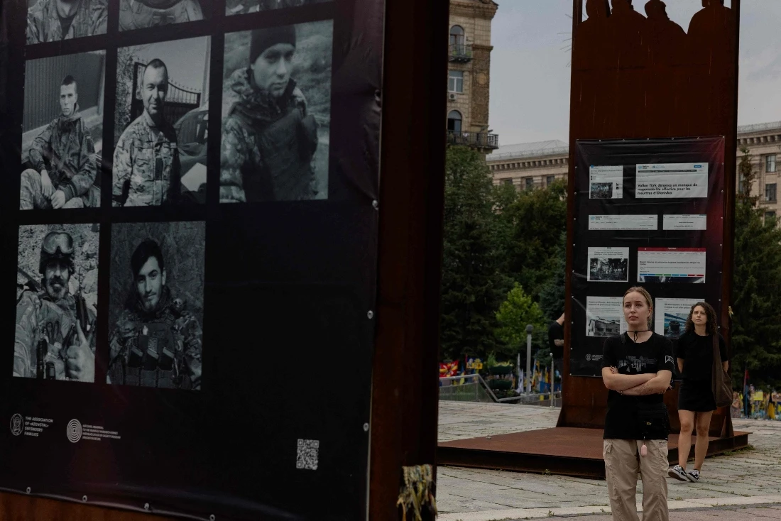 Ukrainian women look at at an exhibition during a memorial event to mark the third anniversary of the Olenivka prison attack, at Independence Square in Kyiv, Ukraine. (AFP)
