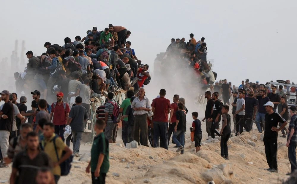 Palestinians climb onto trucks carrying aid supplies, Beit Lahia, Gaza, July 29, 2025. (Reuters)