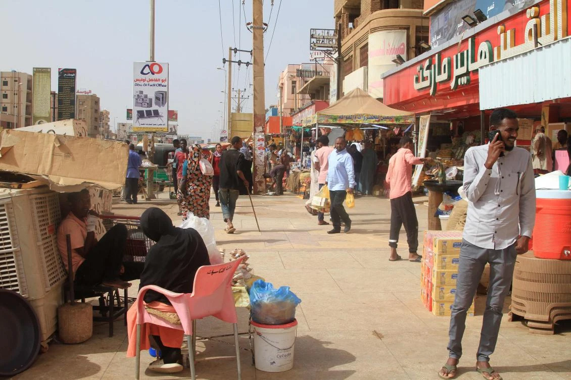 Sudanese walk past shops on a street in in Khartoum's twin city Omdurman on July 29, 2025. (Photo by Ebrahim Hamid / AFP)