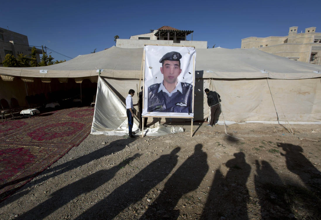 Workers raise a banner with a photo of Jordanian pilot Lt. Mu'ath al-Kaseasbeh, held captive by the Daesh group, outside a tent for supporters in Amman, Jordan, on Jan. 30, 2015. (AP Photo/Nasser Nasser, File)