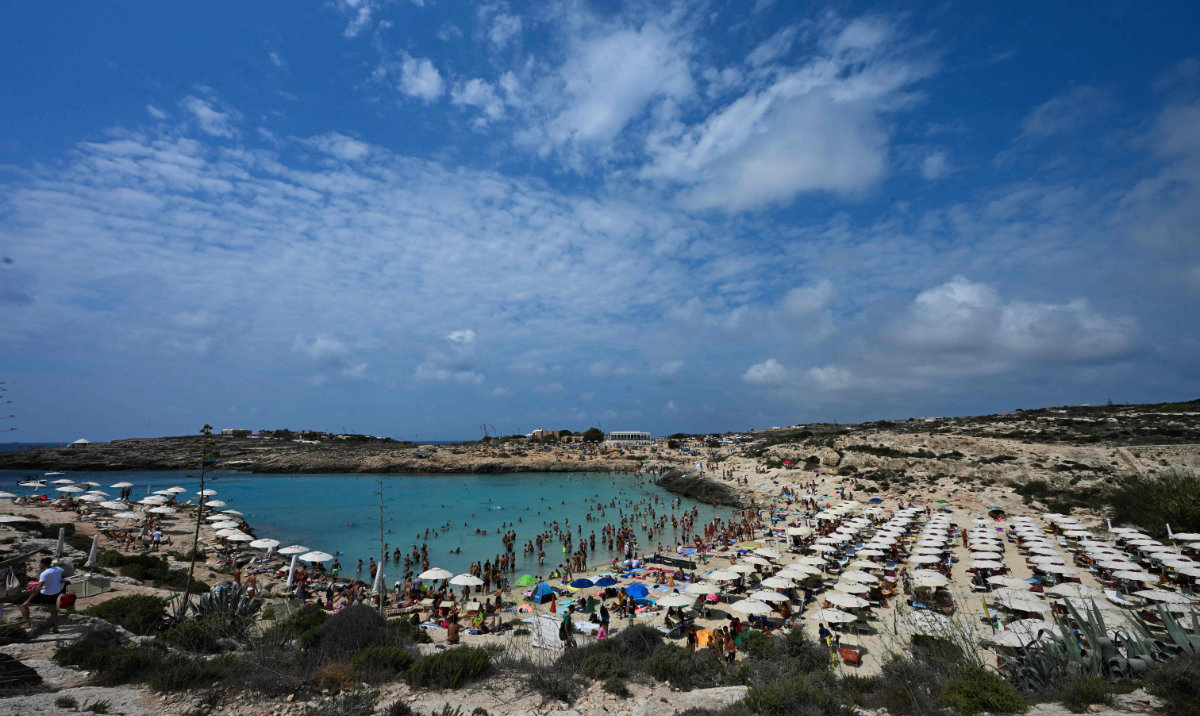 This photograph shows people cooling off at the beach during a heatwave in the island of Lampedusa, south Italy. (AFP)