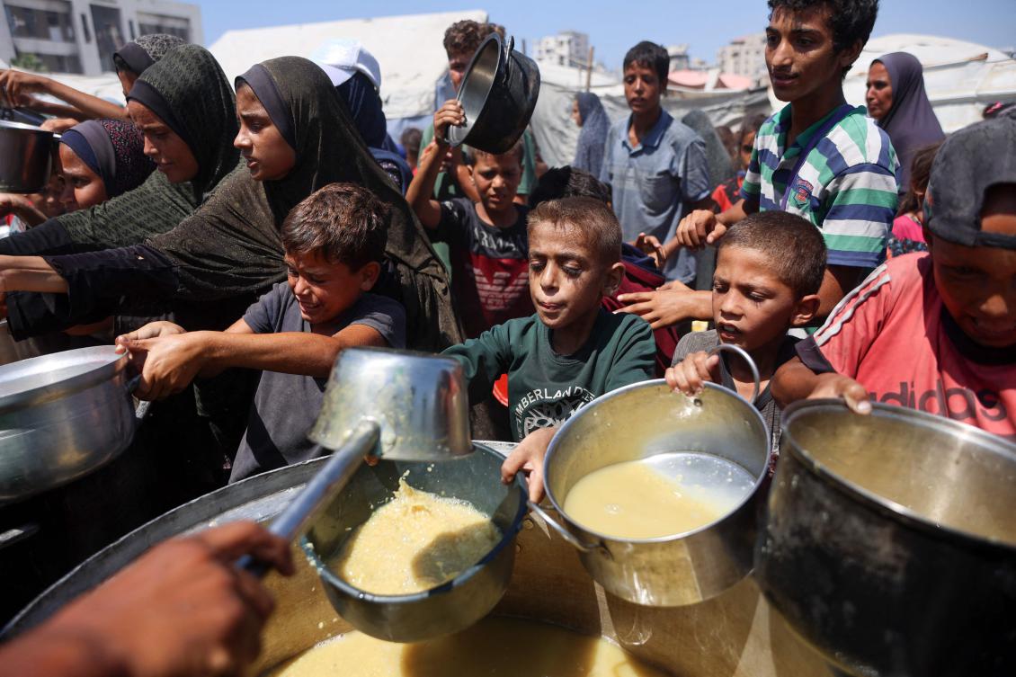 Palestinians receive lentil soup at a food distribution point in Gaza City on August 1, 2025. (AFP)