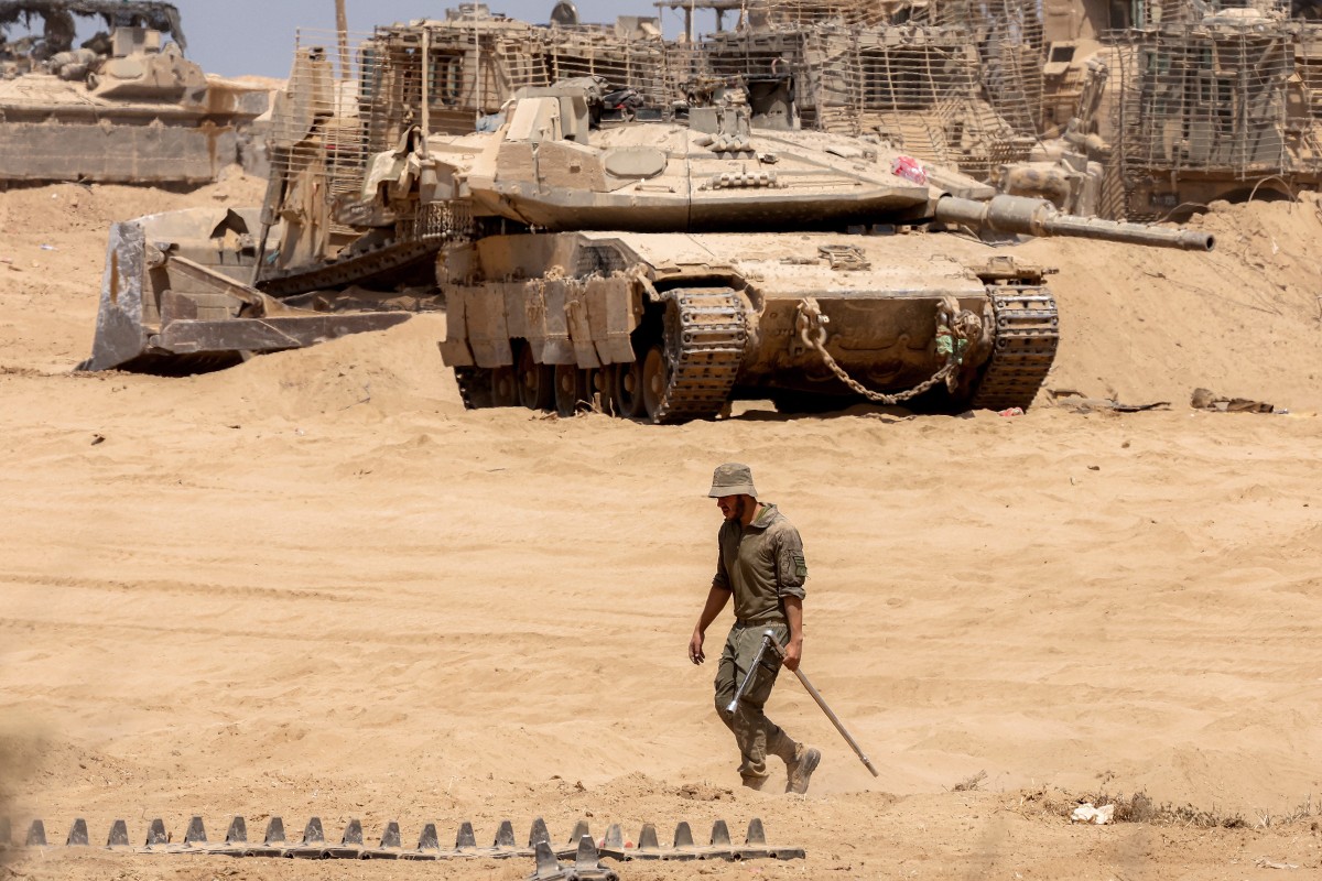An Israeli army soldier walks near a main battle tank deployed at a position along the border with the Gaza Strip and southern Israel, July 29, 2025. (AFP)