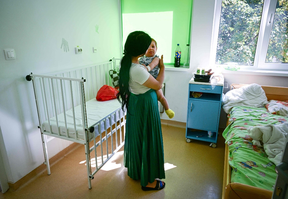 A young mother who does not want to be identified holds her ten months old child suspected to be infected with measels at the county hospital in Piatra Neamt, Romania. (AFP)