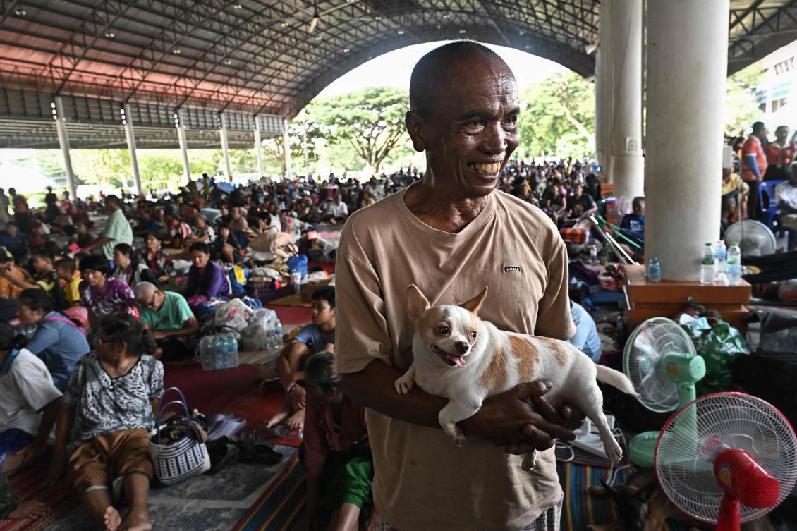 Above, evacuee Sompong Krueakaew with his pet dog as military attaches and diplomats from 23 foreign countries visit an evacuation center in the Thai border province of Sisaket on Aug. 1, 2025. (AFP)