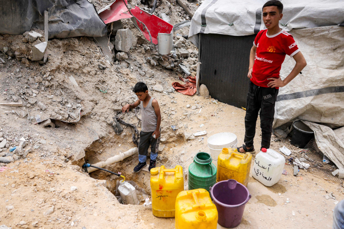 A boy fills up containers with water from the remaining water still left in underground pipes, in Beit Lahia in the northern Gaza Strip on April 24, 2025. (AFP)
