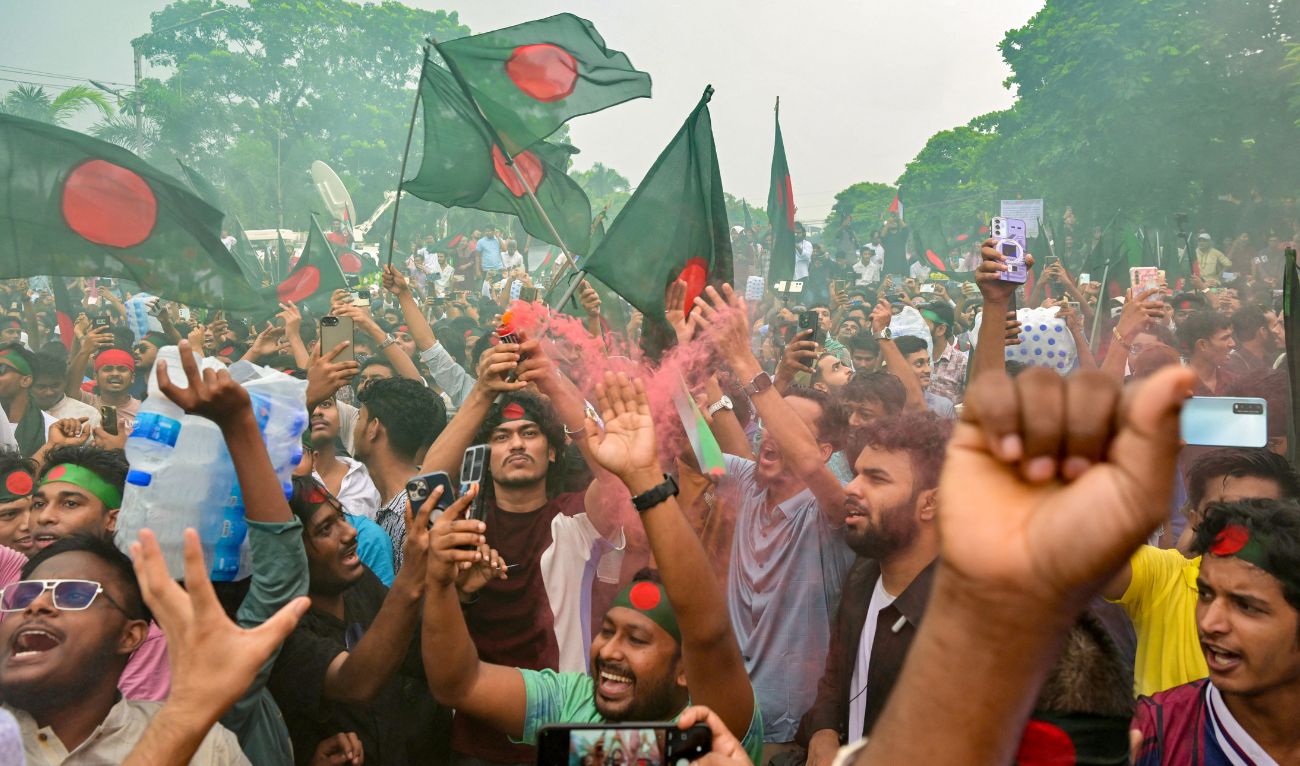 People hold Bangladesh's national flag as they celebrate during a government-organised event in Dhaka on August 5, 2025. (AFP)