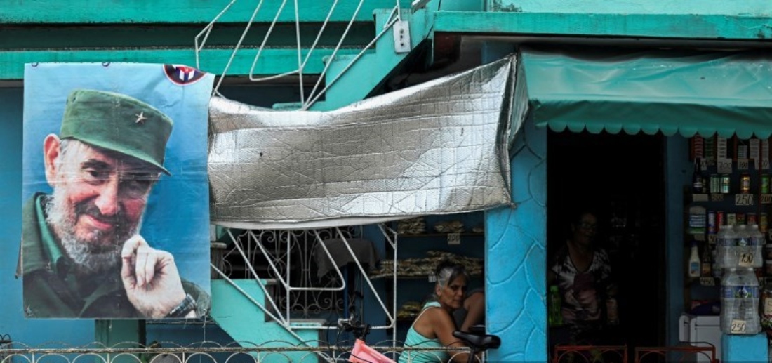 A woman sits near a poster of late Cuban leader Fidel Castro in Jatibonico, Cuba. (AFP)