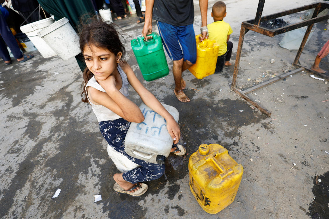 A Palestinian girl waits with containers to collect water amid shortages, in Gaza. (REUTERS)