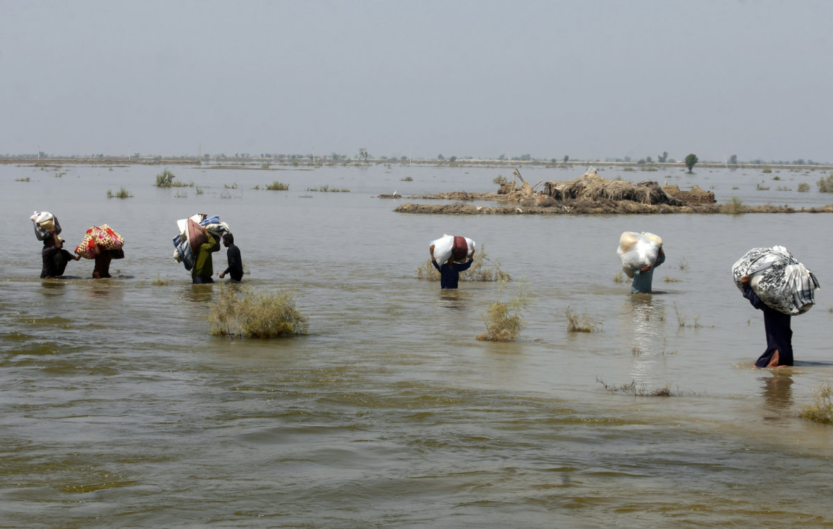 Victims of heavy flooding from monsoon rains carry relief aid through floodwater in the Qambar Shahdadkot district of Sindh Province, Pakistan, on Sept. 9, 2022. (AP Photo/File)