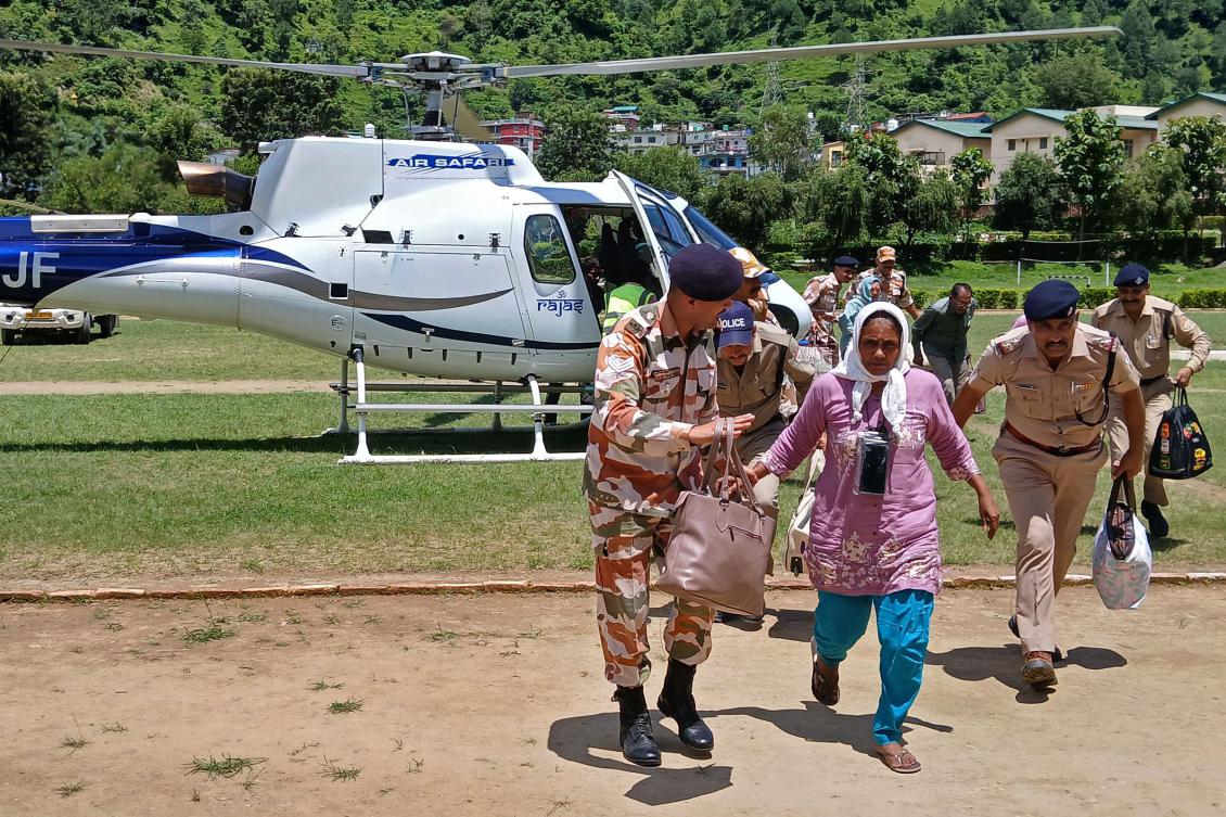 Indian security personnel escort people deboarding a helicopter after they were evacuated during a rescue operation, at the Indo-Tibetan Border Police (ITBP) camp in Uttarkashi district on Aug. 7, 2025. (AFP)