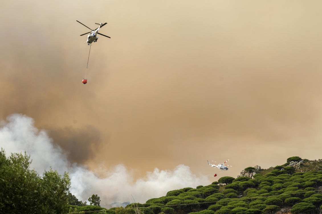 Firefighting helicopters drop water to extinguish a blaze in Torre de la La Peaa near the southern Spanish tourist town of Tarifa. (Europa Press via AP)