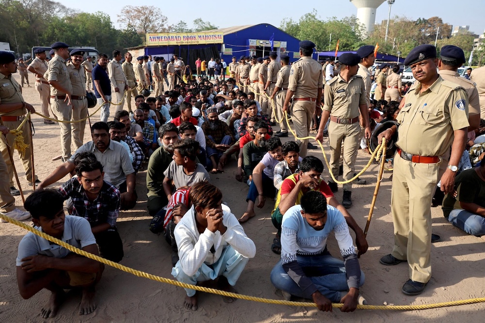 Police officers stand next to men they believe to be undocumented Bangladeshi nationals after they were detained during raids in Ahmedabad, India on April 26, 2025. (Reuters)