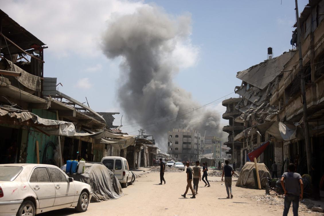 Palestinians watch as a plume of smoke rises during an Israeli strike on Gaza City’s southern Al-Zeitoun neighborhood on August 8, 2025. (AFP)
