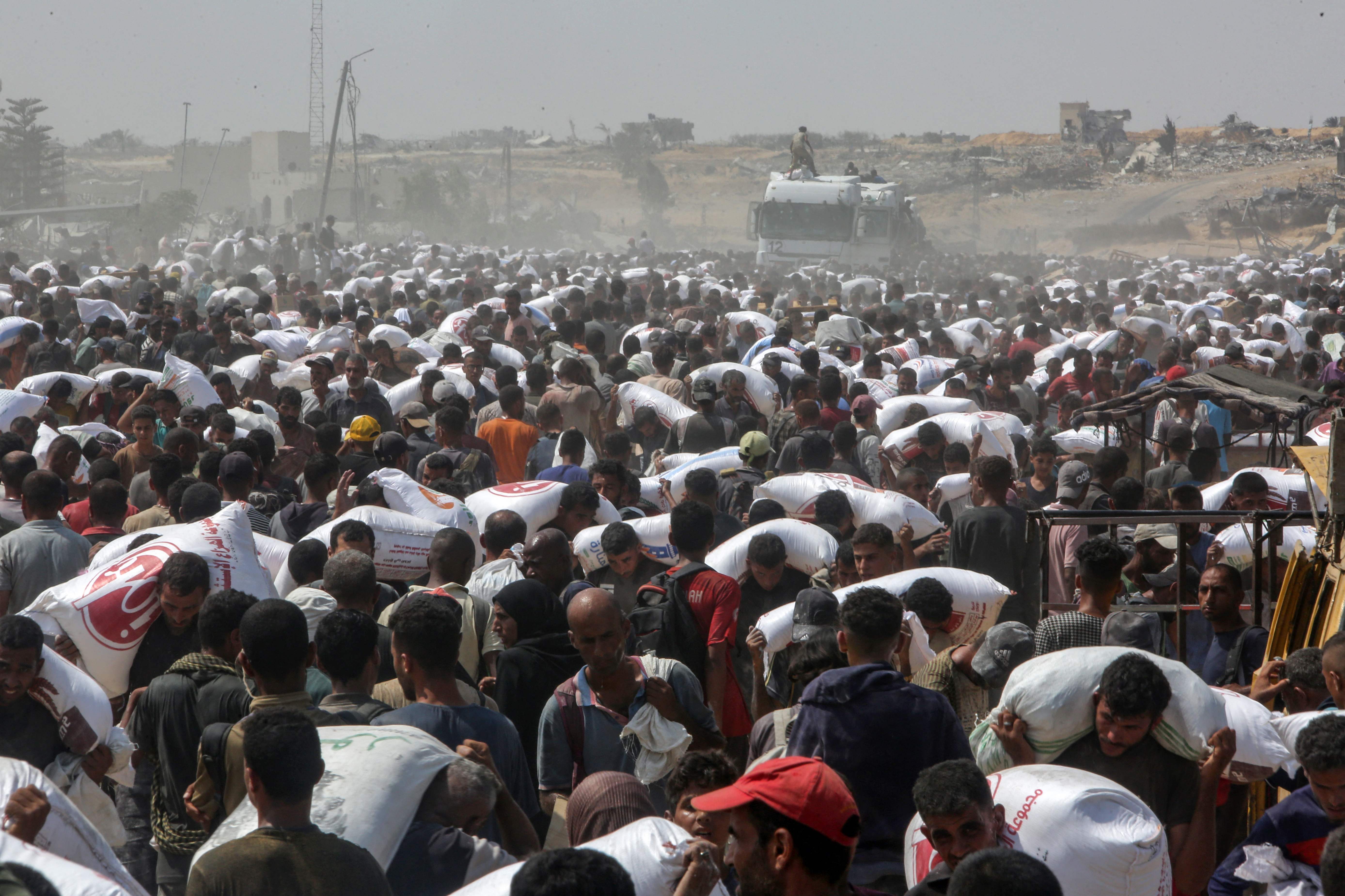 Palestinians carry food parcels from humanitarian aid trucks in Khan Yunis, in the southern Gaza Strip on Saturday. (AFP)