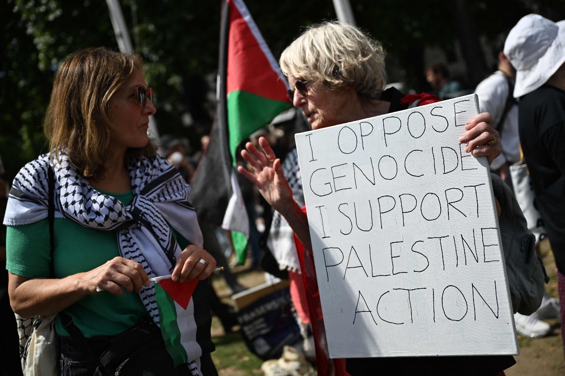 Protesters chat, one holding a placard in support of Palestine Action in Parliament Sqaure ahead of a "Lift The Ban" demonstration in n Parliament Square, central London, UK. (AFP)
