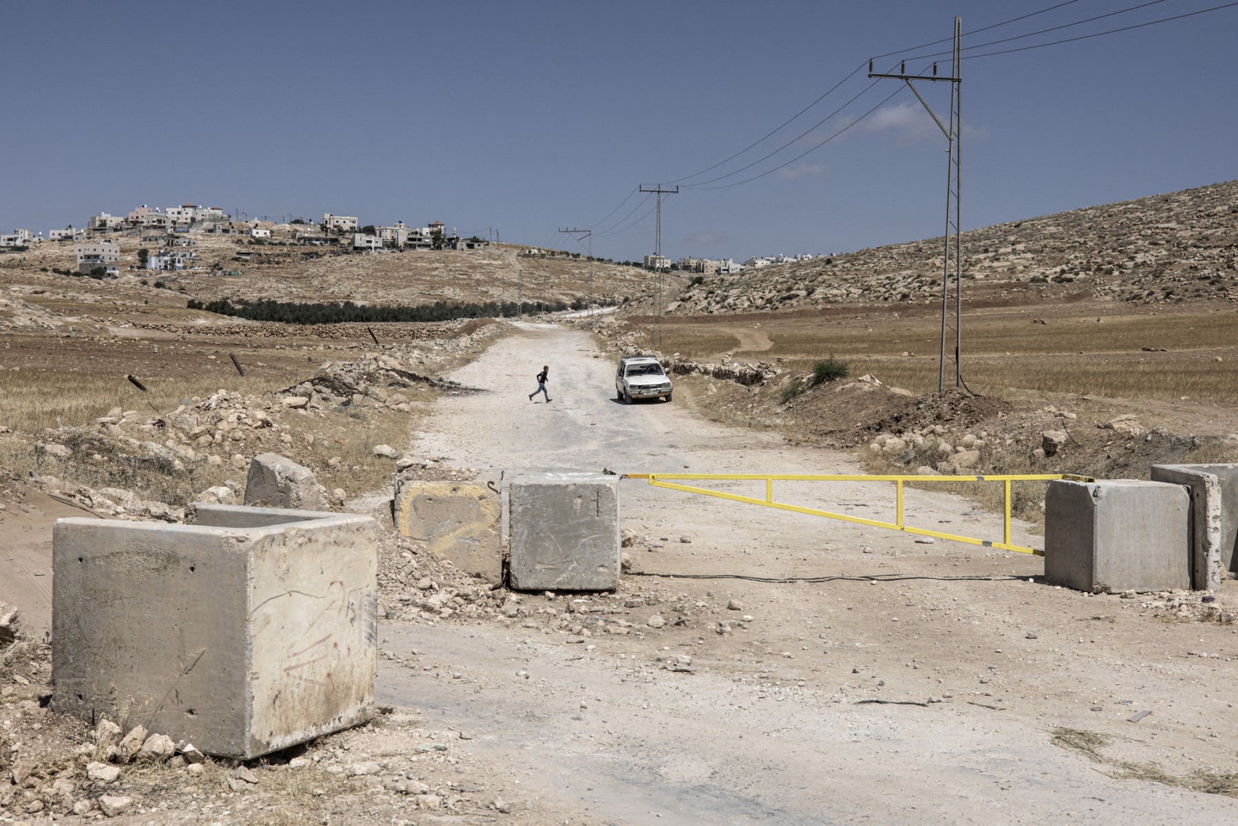 A young boy runs across a road closed by an Israeli yellow security gate in the Masafer Yatta area in the occupied West Bank, June 2, 2025. (AFP)