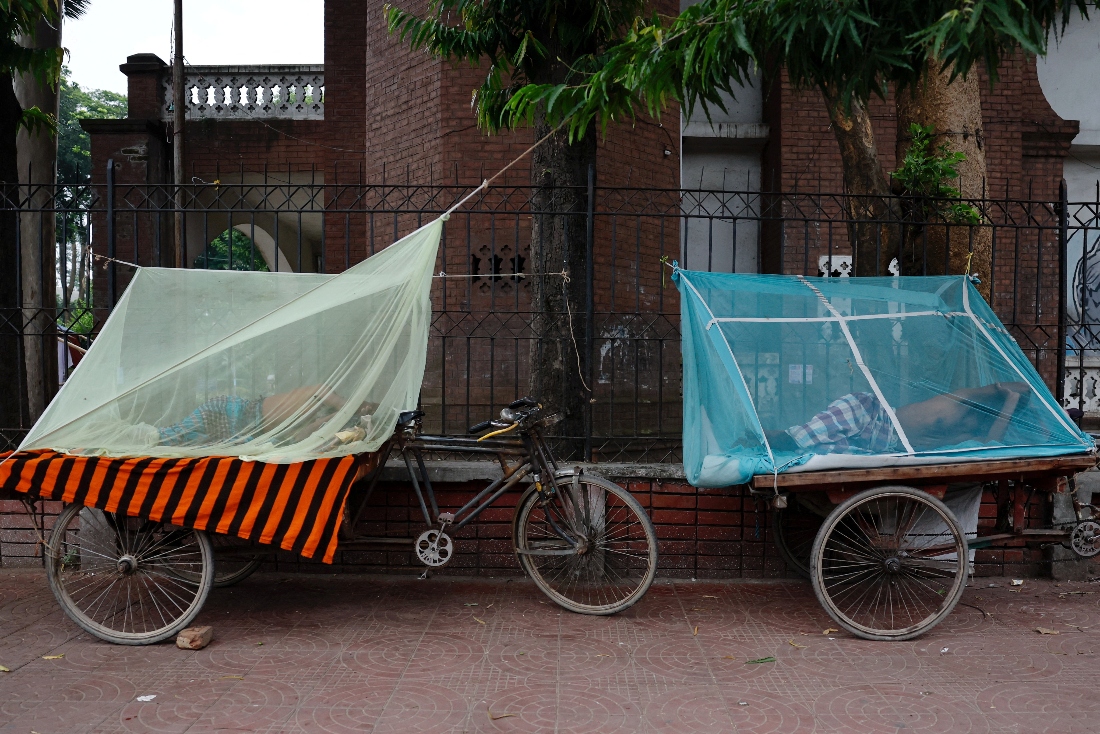 People sleep on three wheeler carts using mosquito nets in Dhaka, Bangladesh. (Reuters)