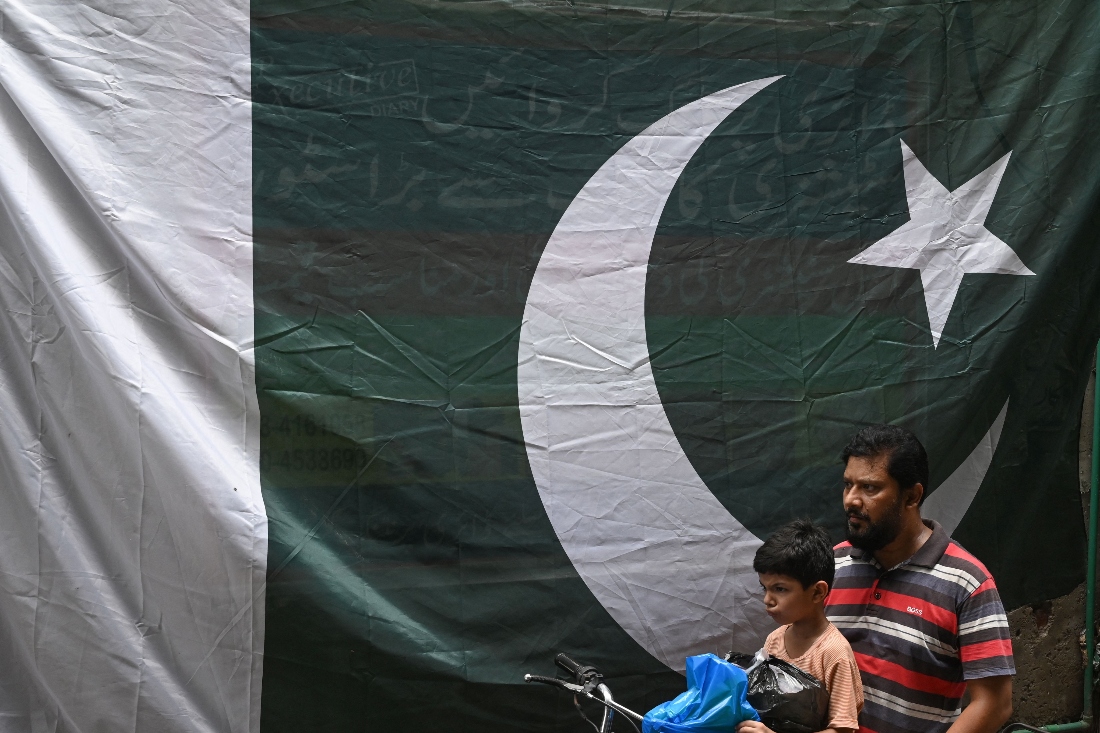 A man riding a motorbike passes by a Pakistani flag ahead of the country's Independence Day celebrations, in Lahore, Pakistan. (AFP)
