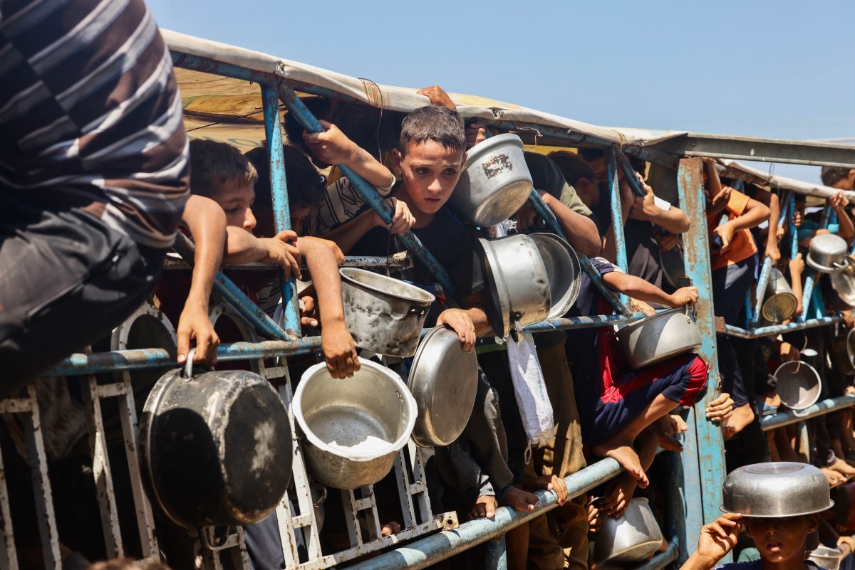 Palestinian children wait for a meal at a charity kitchen in the Mawasi area of Khan Yunis in the southern Gaza Strip. (File/AFP)