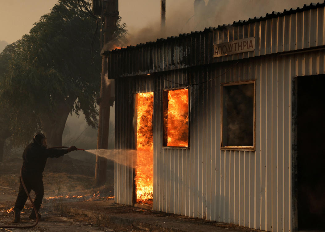 A firefighter works to extinguish a fire from an building during a wildfire, in Sichaina near Patras, Greece. (REUTERS)