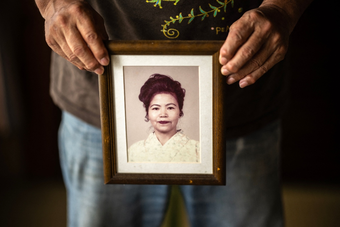 Takemasa Kinjo, who was a high school student when his mother was killed by a US Marine in 1974, holding her portrait during an interview with AFP at his residence in the Henoko area of Nago city, Okinawa Prefecture. (AFP)