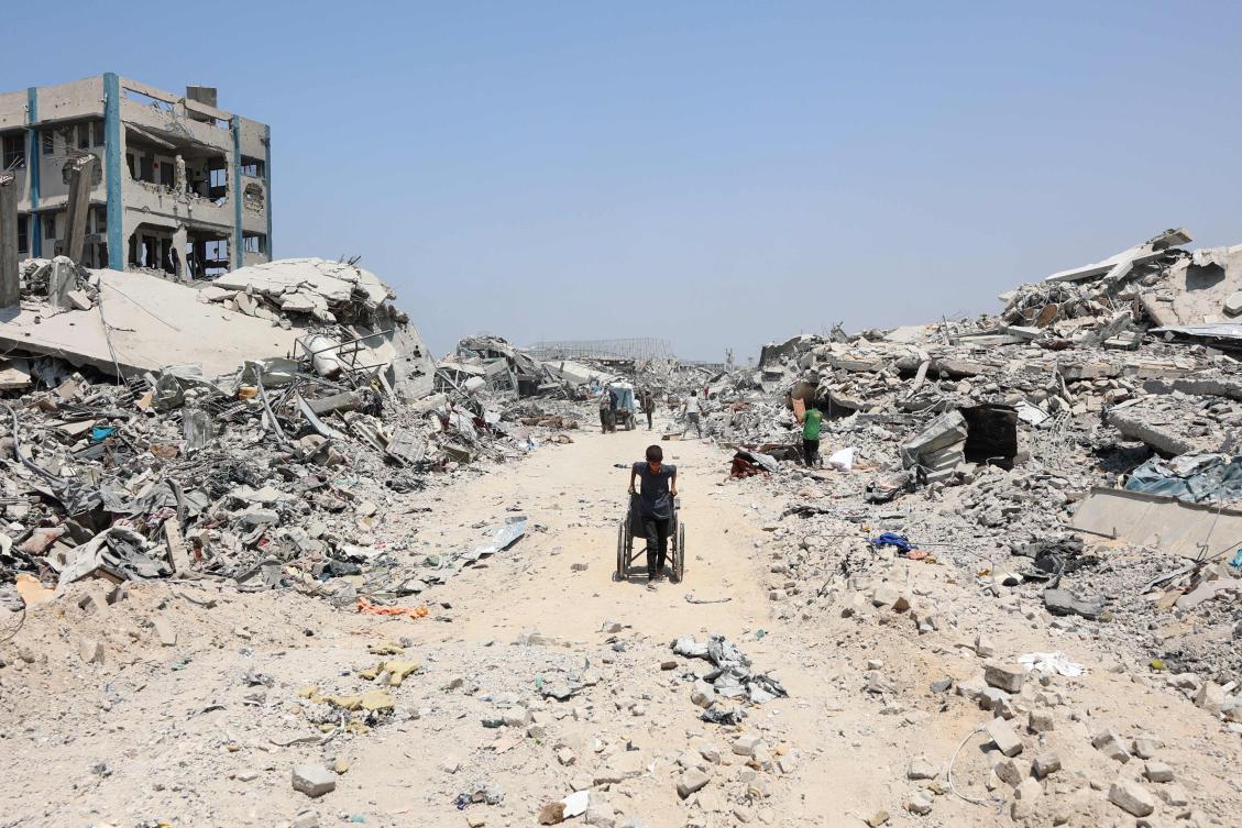 A Palestinian boy pulls a wheelchair past destroyed buildings in the Al-Tuffah neighbourhood of Gaza City on Thursday. (AFP)