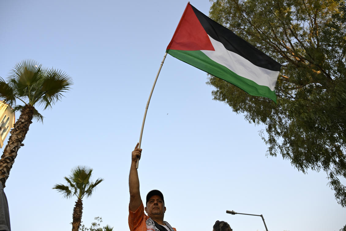 A protester waves a Palestinian flag during a rally to protest the arrival of a cruise ship with Israelis, in Piraeus port, Greece, Aug. 14, 2025. (AP)