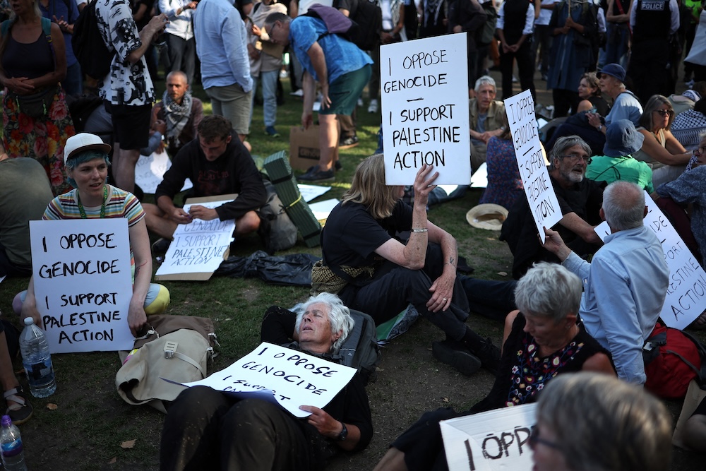 Protesters sit with placards supporting of Palestine Action at a demonstration in Parliament Square, central London on Aug. 9, 2025. (AFP)